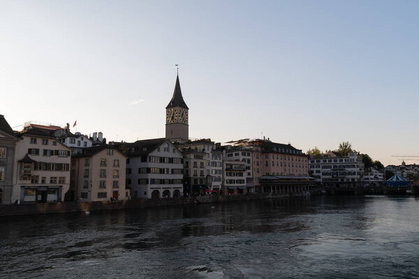 Zurich, Switzerland, September 4, 2021 Promenade at the river Limmat with the tower of a church in the background