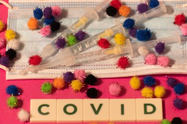 Vaduz, Lihtenştayn, 17 Aralık 2021 Virüs parçacıkları tıbbi yüz maskelerinde şırıngalarla ve Covid yazısıyla