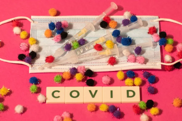 Vaduz, Lihtenştayn, 17 Aralık 2021 Virüs parçacıkları tıbbi yüz maskelerinde şırıngalarla ve Covid yazısıyla