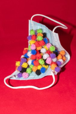 Vaduz, Lihtenştayn, 17 Aralık 2021 Kırmızı arka planda farklı virüs varyasyonları olan tıbbi yüz maskesi