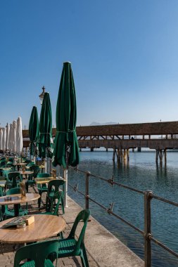 Lucerne, İsviçre, 10 Mart 2022 Şemsiye ve masalar şehir merkezindeki su gezinti alanında bir restoranda
