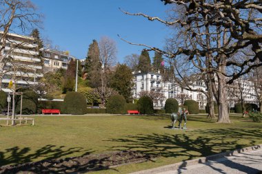 Lucerne, İsviçre, 10 Mart 2022 Idyllic yeşil parkında güneşli bir günde arka planda binalar