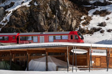 Davos, İsviçre, 23 Mart 2022 Yerel tren şehir merkezine giden karlı bir kış manzarasının yanından geçiyor.