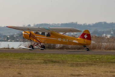 Wangen-Lachen, İsviçre, 27 Mart 2022 Piper PA18-180M Super Cub pervaneli uçak küçük bir havaalanına iniyor.