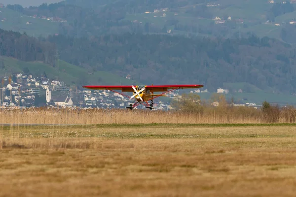 Wangen-Lachen, İsviçre, 27 Mart 2022 Piper PA18-180M Super Cub pervaneli uçak küçük bir havaalanına iniyor.