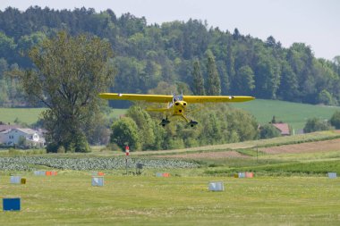 Lommis, Switzerland, May 11, 2022 Yellow Piper PA18-150 Super Cub propeller plane is taking off from a small airfield
