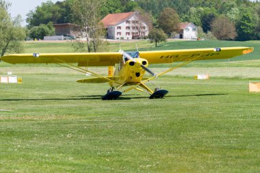 Lommis, İsviçre, 11 Mayıs 2022 Piper PA18-150 Super Cub pervaneli uçak küçük bir havaalanındaki çimlerin üzerinde taksicilik yapıyor.,