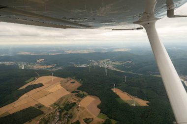 Collenberg, Bavaria, Germany, July 10, 2022 Wind energy turbines are rotating on a green hill seen from a small plane