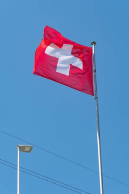 Truebbach, Switzerland, April 28, 2022 Swiss national flag is waving in the wind on the rhine bridge at the border to Liechtenstein