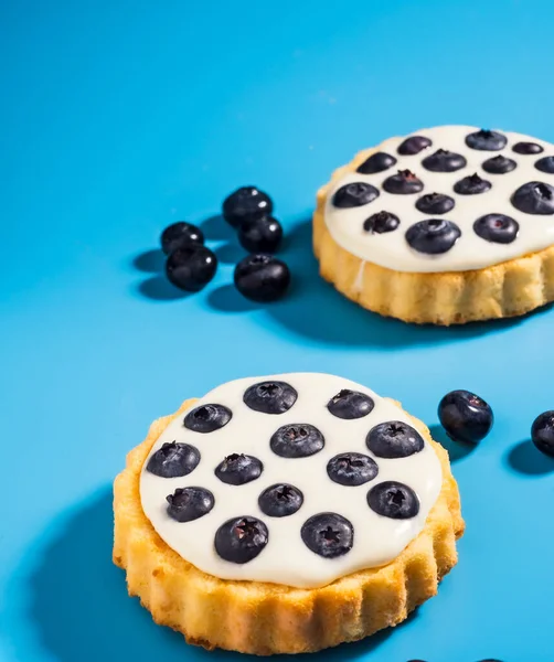 Mavi arka planda kremalı ve yaban mersinli tart.