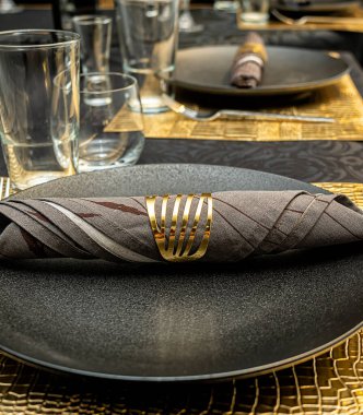 Üzerinde yüzük olan bir peçetenin üstündeki siyah bir plaka.. 