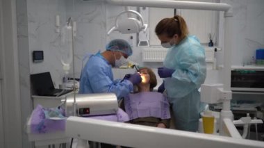 Diş hekimi, yaşlı bir kadına implant yerleştirme ameliyatı yapıyor.