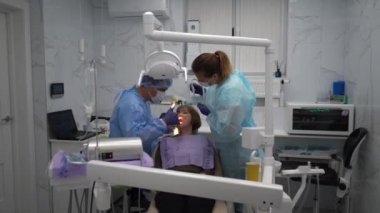 Diş hekimi, yaşlı bir kadına implant yerleştirme ameliyatı yapıyor.