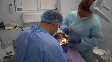 Diş hekimi, yaşlı bir kadına implant yerleştirme ameliyatı yapıyor.