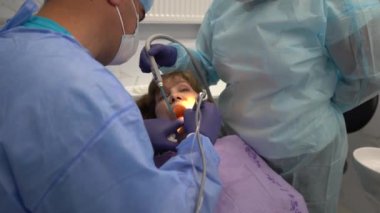 Diş hekimi, yaşlı bir kadına implant yerleştirme ameliyatı yapıyor.