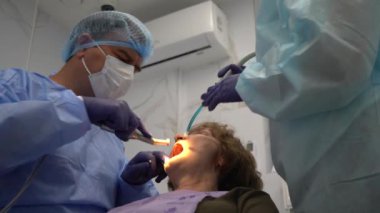 Diş hekimi, yaşlı bir kadına implant yerleştirme ameliyatı yapıyor.