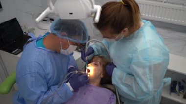 Diş hekimi, yaşlı bir kadına implant yerleştirme ameliyatı yapıyor.