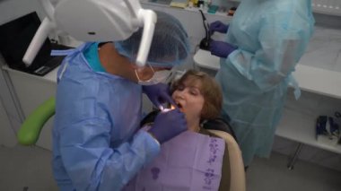 Diş hekimi, yaşlı bir kadına implant yerleştirme ameliyatı yapıyor.
