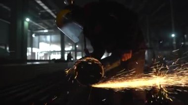 Profesyonel erkek işçi öğütme makinesiyle metal kesiyor.