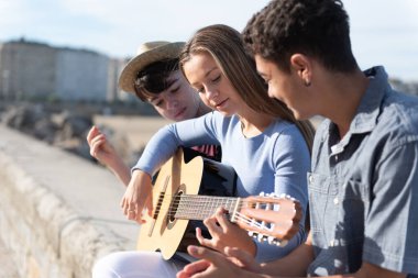 Açık havada gitar çalan lise öğrencileri..