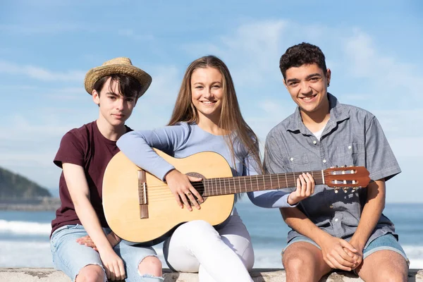 Gruppo Adolescenti Multietnici Seduti Mare Con Chitarra Guardando Macchina Fotografica — Foto Stock