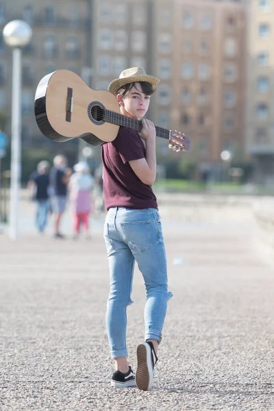 Omzunda gitar tutan yakışıklı genç müzisyenin portresi.