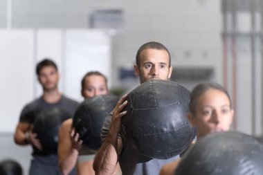 Spor merkezinde ilaç toplarıyla çalışan bir grup sporcu.
