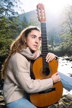 Parkta gitar tutan müzisyen kadın.