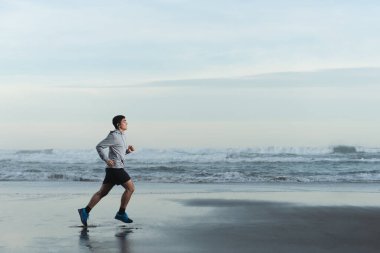 Hispanic teenager runner training at the beach.