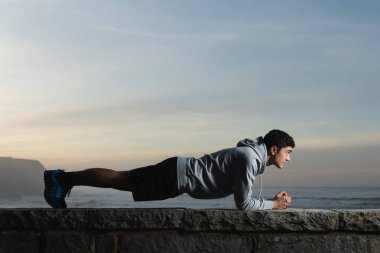 Hispanic teenager making a plank exercise to train his core and abdominal muscles. Healthy lifestyle in adolescence concept.