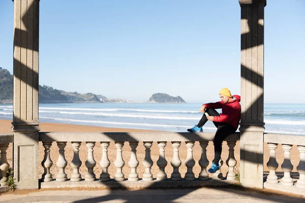 年轻的拉丁裔男子坐在海滨 一边放松一边用手机 — 图库照片