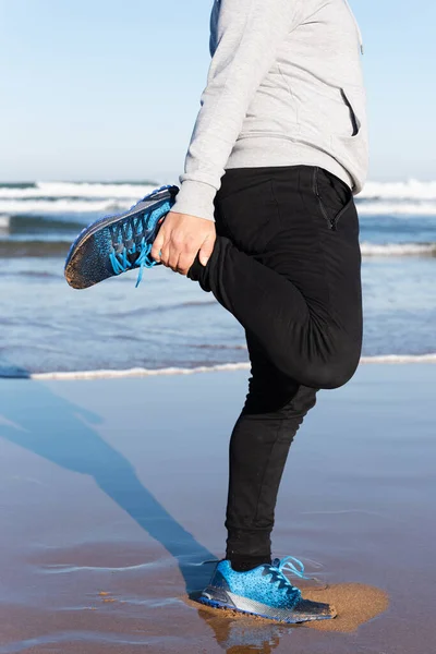 Faceless man stretching quadriceps muscle at seaside