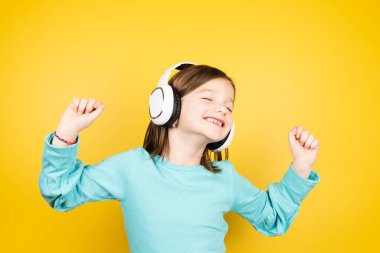 Mutlu küçük çocuk müzik dinliyor ve gözleri kapalı dans ediyor..