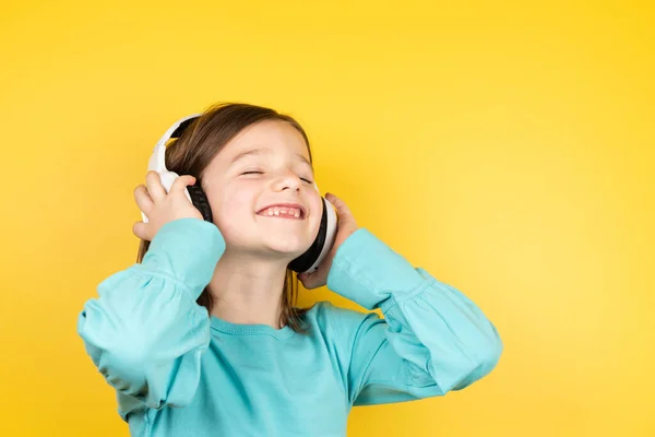幸せな笑顔の女の子はヘッドフォンで音楽を聴く — ストック写真