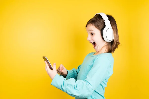 幸せな女の子は彼女の携帯電話の内容に驚いている 子供の頃の概念に関するデジタル中毒とドーパミン — ストック写真