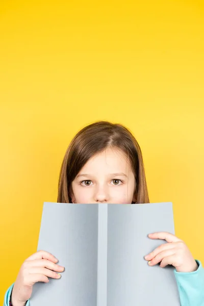 Barnet Håller Bok Och Tittar Kameran Gult Kopieringsutrymme — Stockfoto