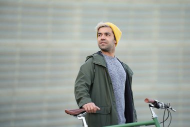 İspanyol adam bisikleti tutuyor ve arkasına bakıyor.