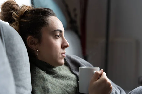 Mujer Joven Preocupada Sosteniendo Una Taza Café Caliente Sofá — Foto de Stock