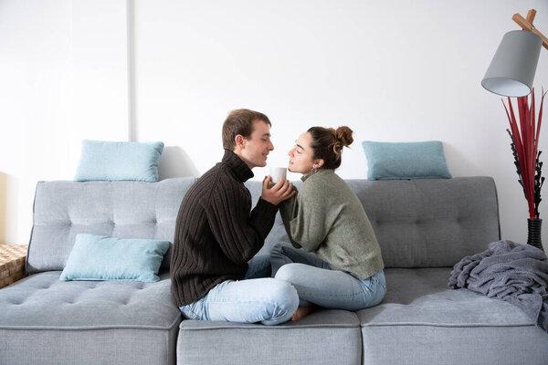 Романтическая пара, сидящая на диване и пьющая кофе