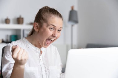 Heyecanlı genç bayan laptopta iyi sonuçlar alıyor.