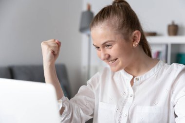 Genç kadın laptopun önünde başarıyı kutluyor..