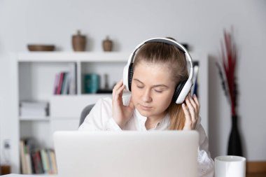 Genç öğrenci müzik dinliyor ve dizüstü bilgisayarın önünde dinleniyor.