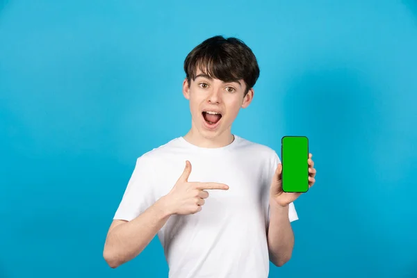 十代の男の子ポインティング緑のクロマスクリーンの電話 — ストック写真