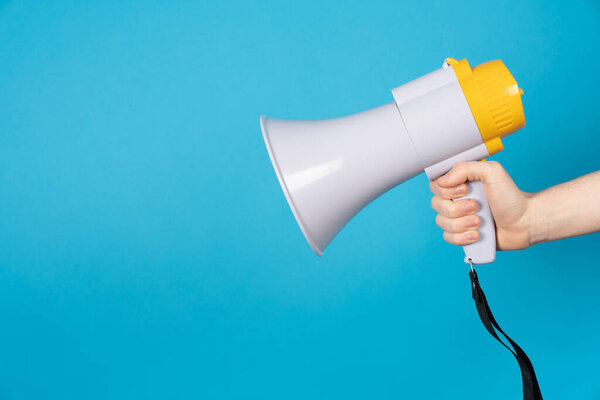 Рука держит мегафон изолирован на синем фоне.