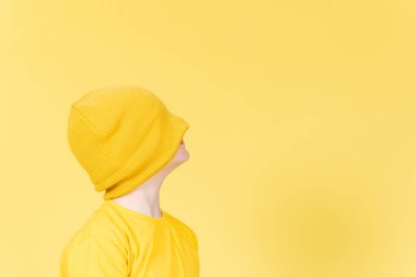 Çocuk sarı yün şapkayla gözlerini kapatıyor. Çocukluk soyut kavramında depresyon