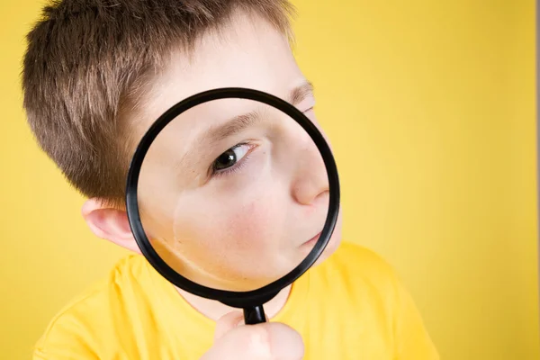 Closeup Boy Looking Camera Loupe Magnifying Glass Isolated Yellow Background — Stock Photo, Image