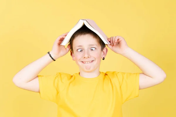 Pojke Som Håller Bok Huvud Och Gör Roligt Ansikte Isolerad — Stockfoto