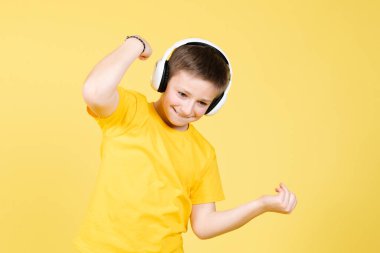 Neşeli pozitif çocuk sarı arka planda müzik ve dans dinliyor..