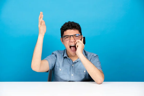 Wściekły Latynoski Nastolatek Krzyczy Przez Telefon Patrzy Kamerę Odizolowaną Niebieskim — Zdjęcie stockowe