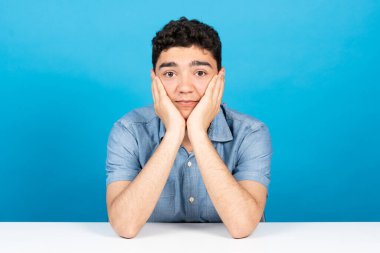 Web kamerasında İspanyol öğrencinin mavi arka planda izole edilmiş sanal sınıfa dikkat ettiği görülüyor. Evde eğitim kavramı.